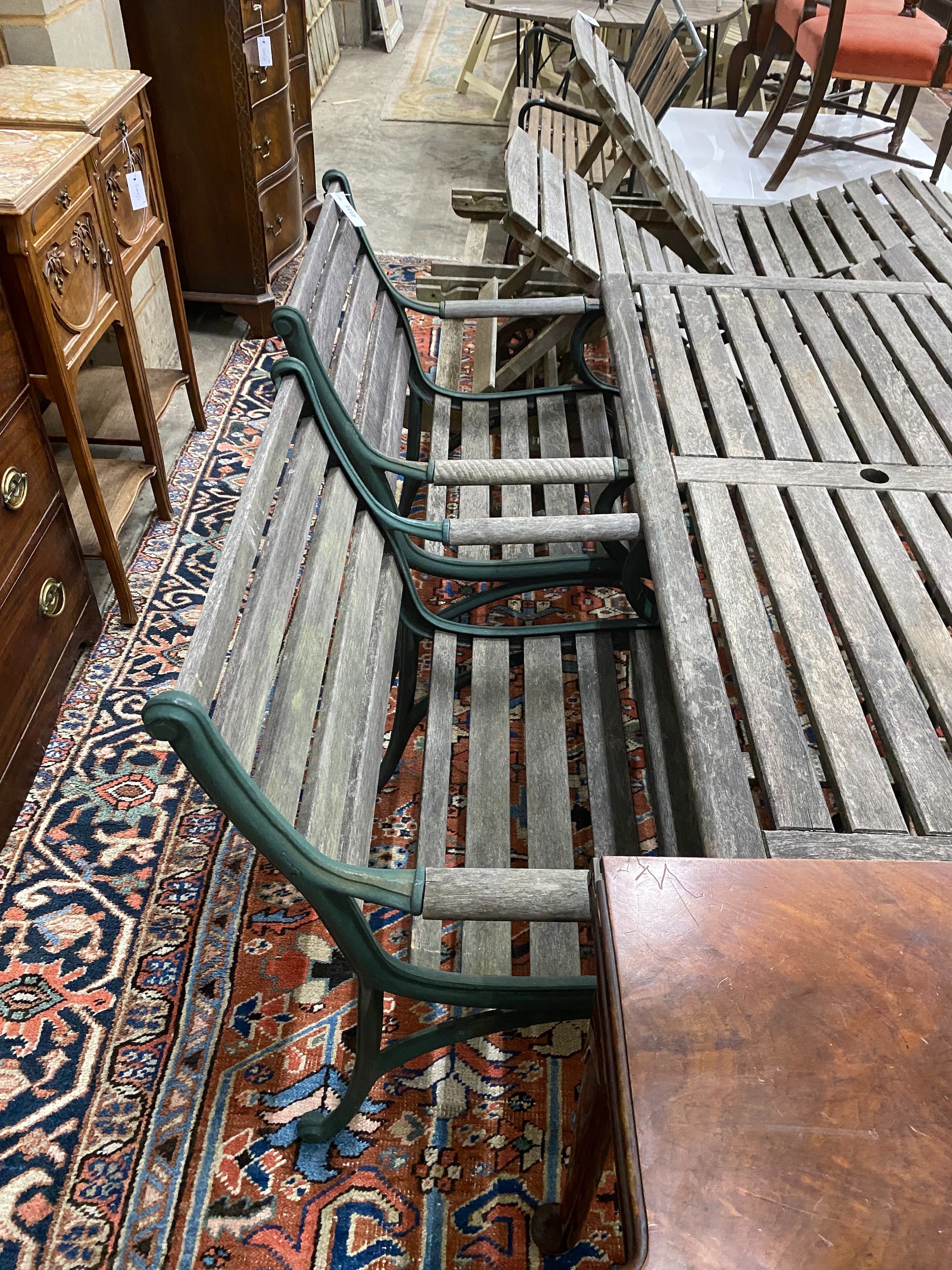 A rectangular slatted wood and cast metal garden table, length 137cm, depth 67cm, height 64cm together with four similar elbow chairs